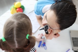 L'otorinolaringoiatra guarda l'orecchio della bambina con l'otoscopio. Test dell'udito nel concetto di bambino