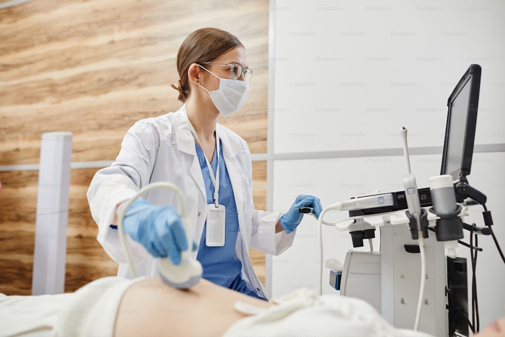 초음파 기계를 사용하고 마스크를 착용한 여의사가 진료실에서 임산부를 진찰하는 모습 초상화