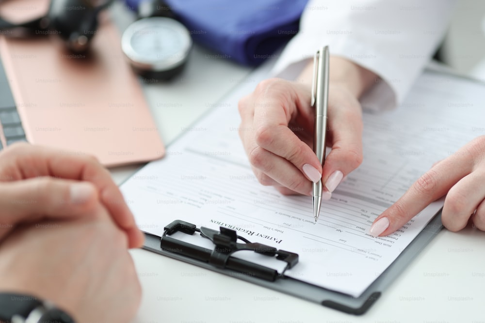 Medic filling out patients medical history in clinic closeup. Doctor visit concept