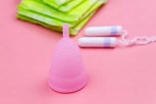 Assorbente, tamponi e coppetta mestruale su sfondo rosa. Concetto di giorni critici, mestruazioni, igiene femminile