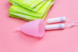 Absorvente, absorvente interno e coletor menstrual em fundo rosa. Conceito de dias críticos, menstruação, higiene feminina