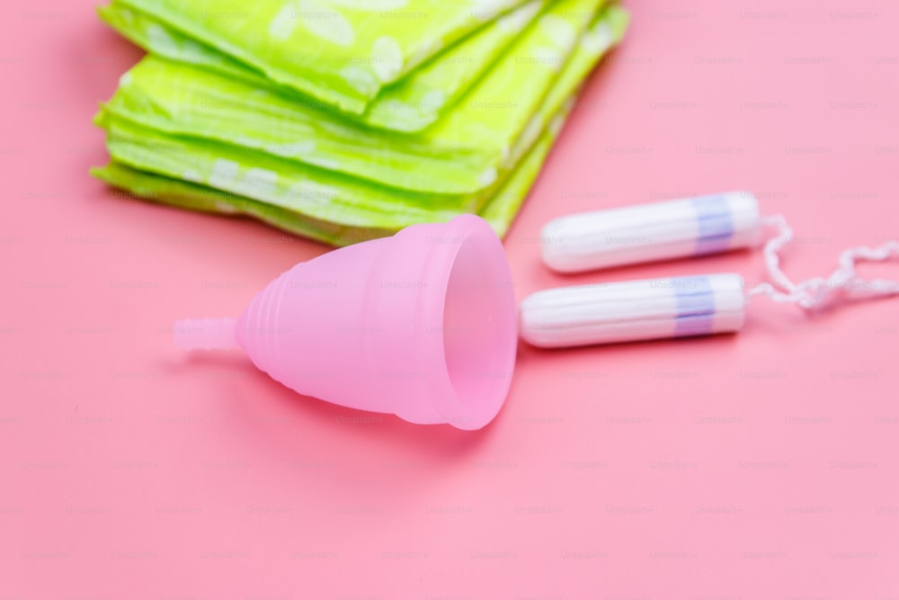 Toalla sanitaria, tampones y copa menstrual sobre fondo rosa. Concepto de días críticos, menstruación, higiene femenina
