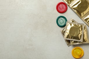 Multicolored condoms on white textured background, space for text