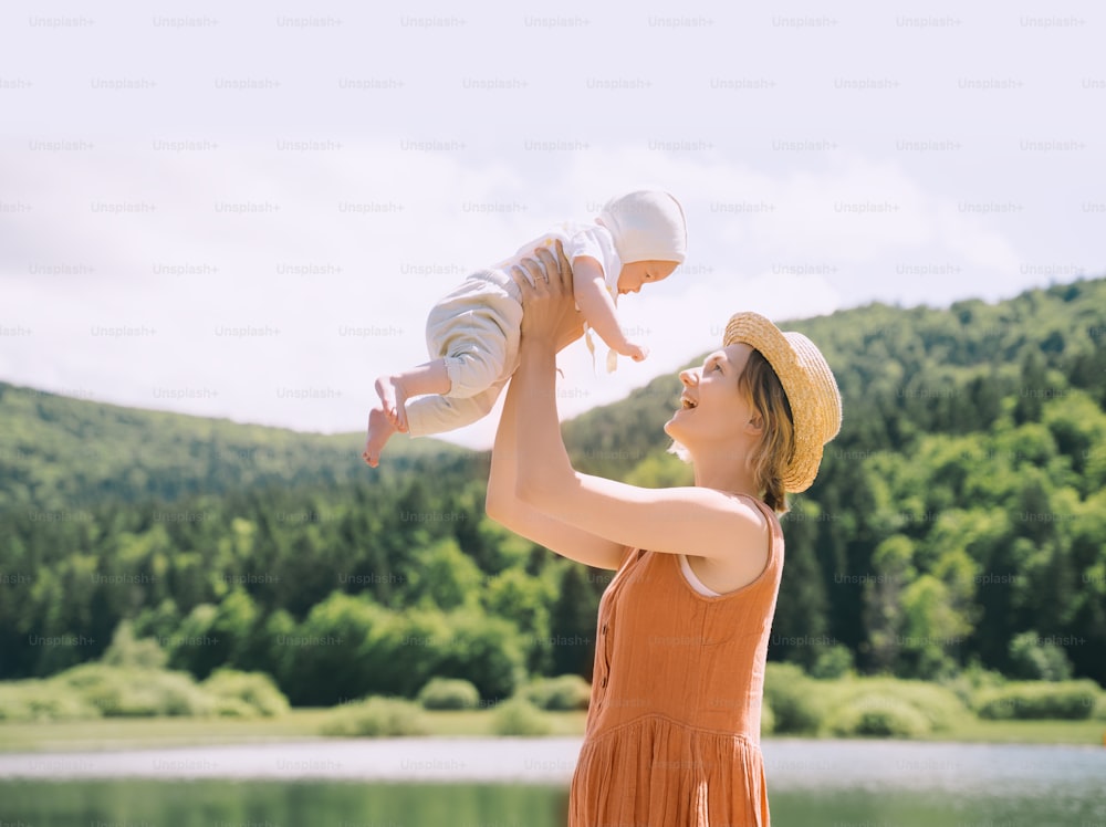 Mother and baby. Concept of natural maternity and motherhood. Beautiful woman and little baby happy together in green nature background. Loving mom with child outdoors.