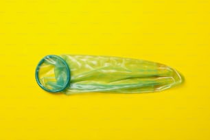 Single mint condom on yellow background, space for text
