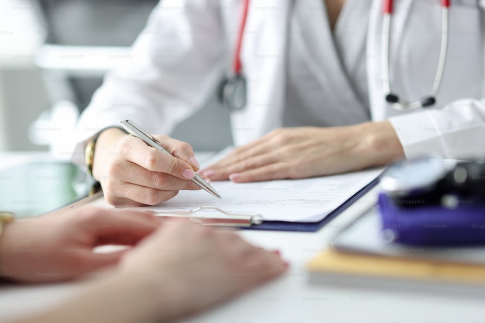 Doctor advising patient and writing in documents closeup. High quality medical care concept