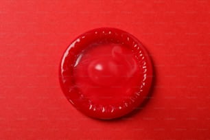 Preservativo rosso singolo su sfondo rosso, vista dall'alto