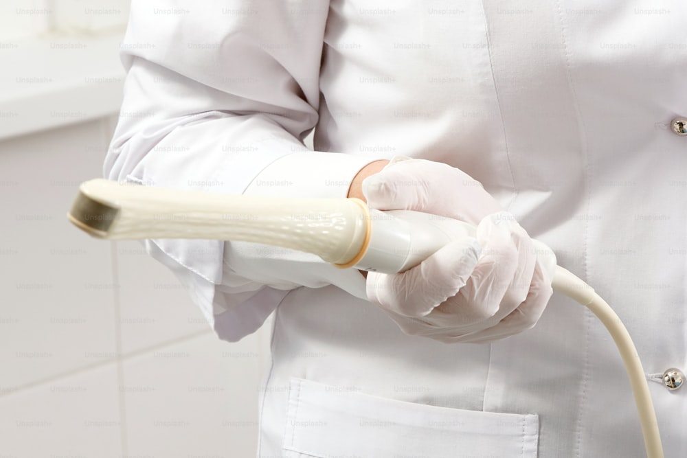 Ginecólogo sosteniendo una varita de ultrasonido transvaginal para examinar a la mujer