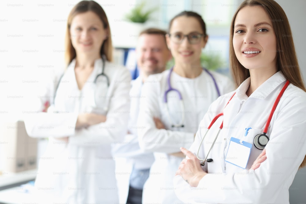 Portrait of young smiling woman doctor on background of colleagues. Teamwork in medicine concept
