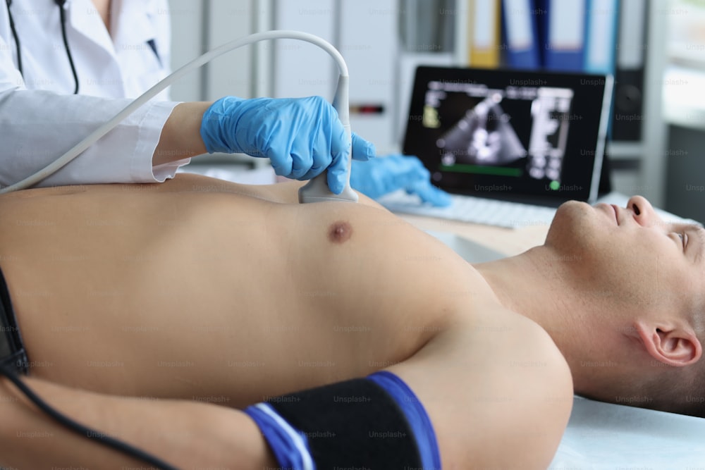 Close-up of doctor doing ultrasound of rib cage, cardiologist examining a patients heart. Person on planned checkup in hospital. Ultrasound and healthcare concept