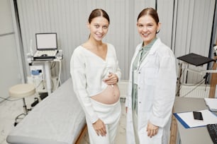Waist up portrait of pregnant young woman posing with female doctor in medical clinic, copy space