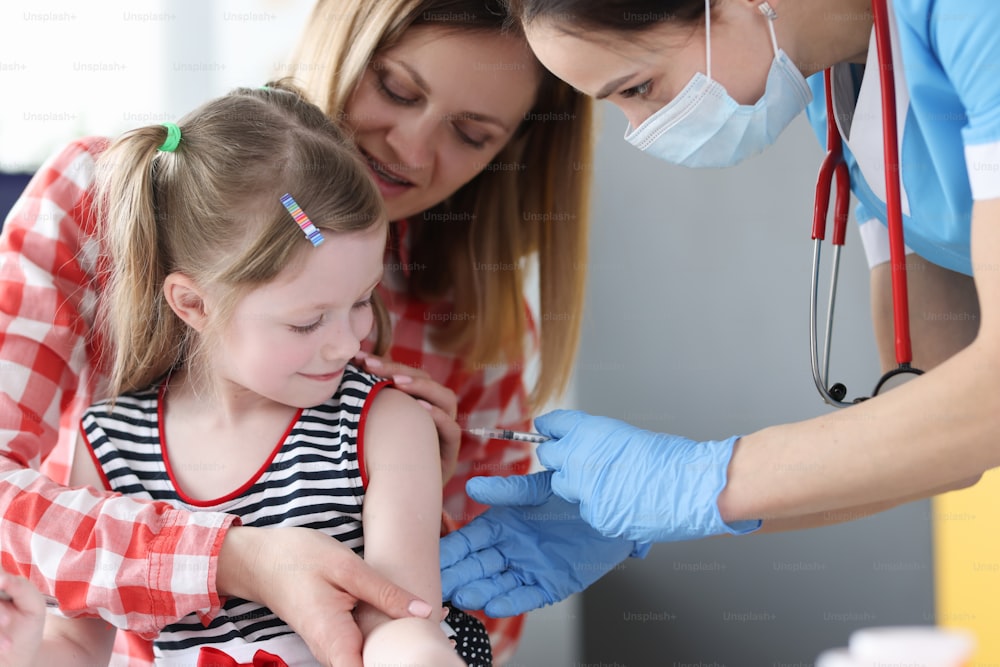 의사가 어린 소녀의 어깨에 백신을 접종합니다. 아기 예방 접종의 혜택 또는 피해 개념