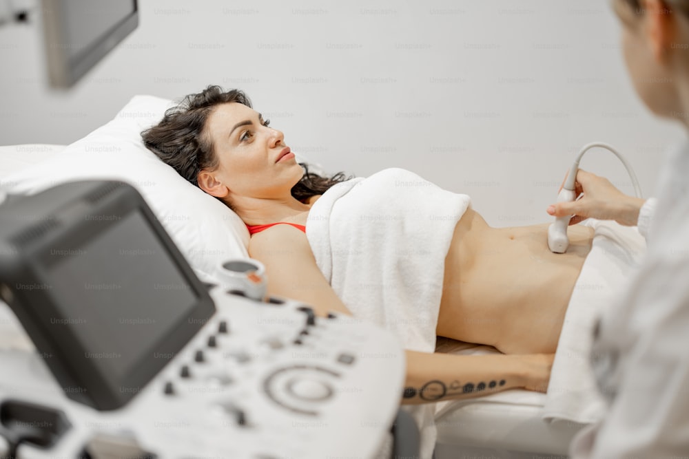Frau bei einer Ultraschalluntersuchung der Bauchhöhle in einer modernen Arztpraxis. Gesundheitskonzept und Untersuchung während der Schwangerschaft