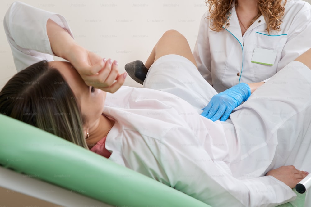 Ginecologo che si prepara per una procedura di esame per una donna seduta su una sedia ginecologica
