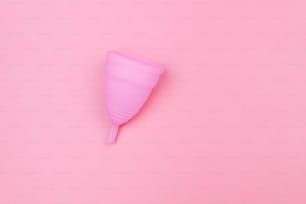 Copa menstrual de silicona reutilizable rosa sobre fondo rosa. Vista superior, espacio de copia. Concepto de higiene, ginecología y salud femenina