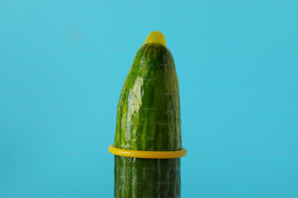 Cucumber with yellow condom on blue background