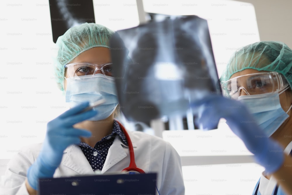 Women doctors stand in the office and look at x-rays of the lungs. Pulmonologists make the diagnosis after examination