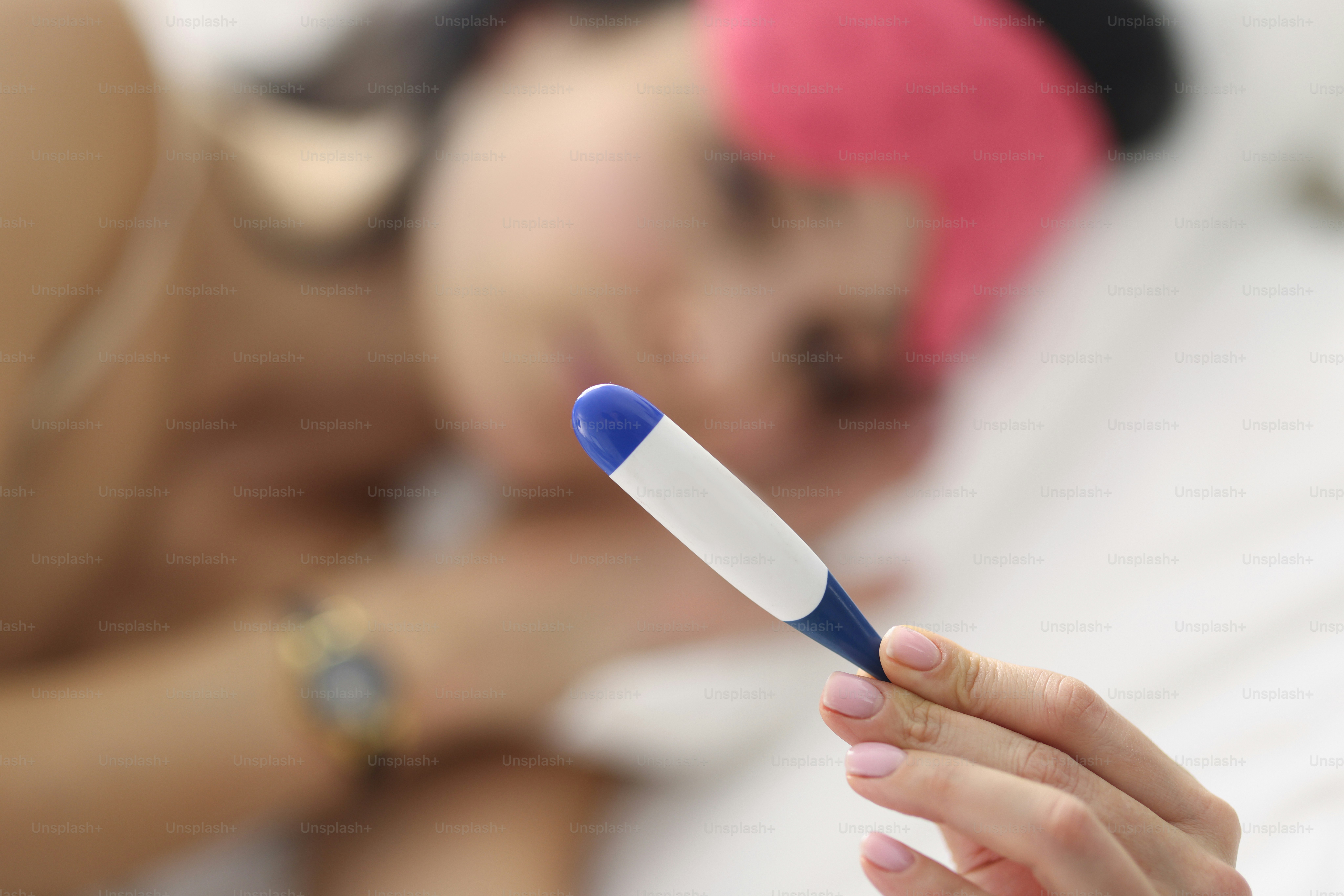 Woman lies on bed and holds thermometer. Hanging fever disease concept