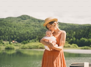 お母さんと赤ちゃん。自然な母性と母性の概念。緑の自然の背景で一緒に幸せな美しい女性と小さな赤ちゃん。屋外で子供を持つ愛情深いお母さん。
