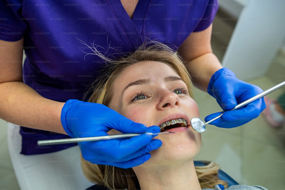 La joven dentista comienza el tratamiento de todos los dientes enfermos en su cliente habitual. Concepto de chica dentista