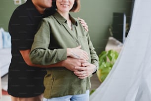 Cropped shot of happy gay couple expecting baby and embracing lovingly in home interior, copy space