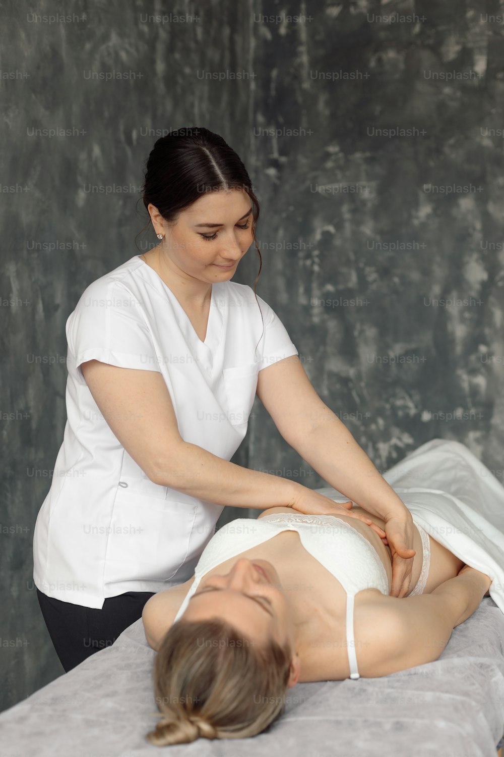 Osteopath in medical cabinet check up ribs of woman lying down on hospital couch in white underwear. Professional specialist appointment and examination. Healthcare and disease treatment concept.
