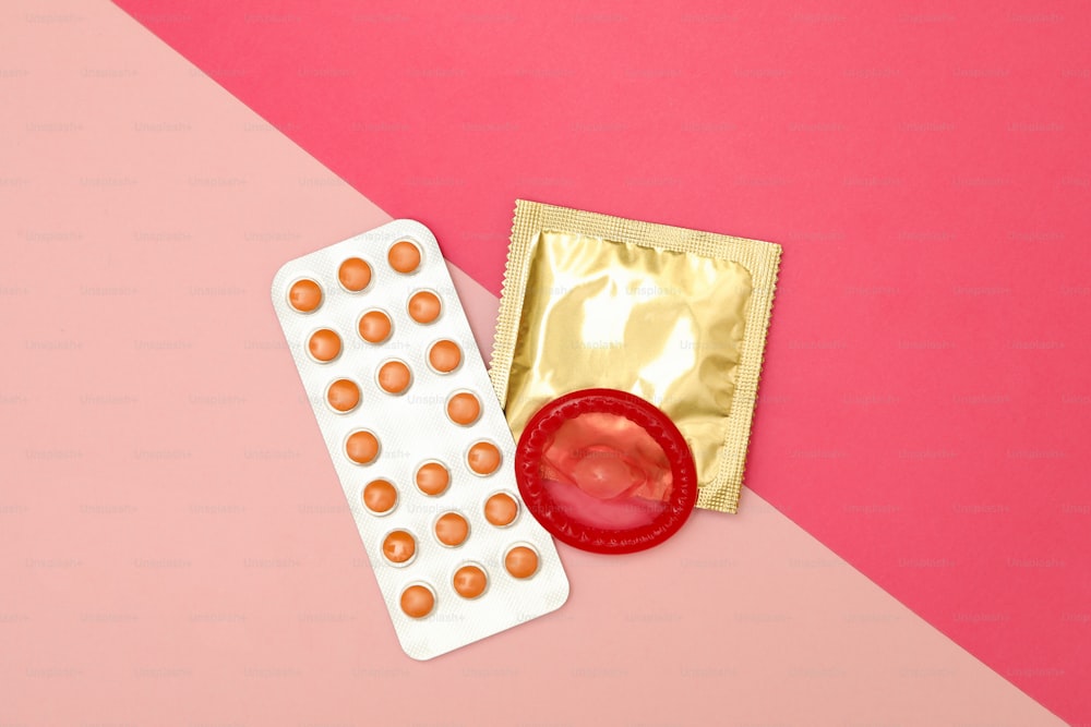 Condoms and pills on two tone background