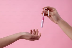 Close up of women hands. One lady giving a tampon in plastic applicator to another