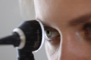 Eye of otorhinolaryngologist looking through otoscope in clinic. Ear disease diagnosis concept
