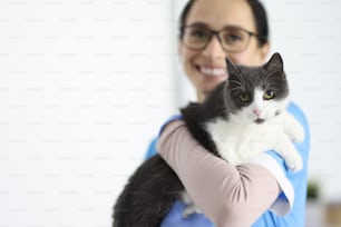 Un veterinario sonriente sostiene a un gato en sus brazos. Concepto de servicios de clínica veterinaria