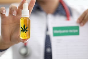 Doctor is holding bottle of hemp extract and prescription. Pain relief in cancer patients with narcotic drugs concept.