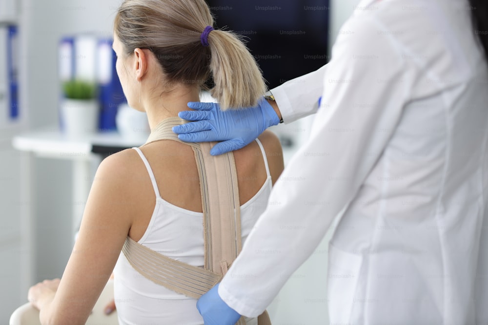 Doctor fixes posture corrector to patient. Slouching, causes, symptoms and treatment