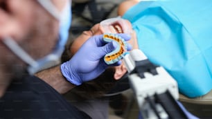 치과 의사는 치과 진료소에서 석고 모델과 환자에 베니어판으로 깁스를 잡고 있습니다. 베니어 개념을 만들기를 위한 인상을 가지고 가기
