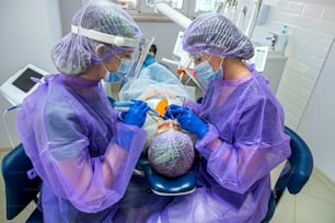 Menina bonita no peitoral de um paciente e óculos UV laranja em uma clínica odontológica. O conceito de tratamento odontológico.