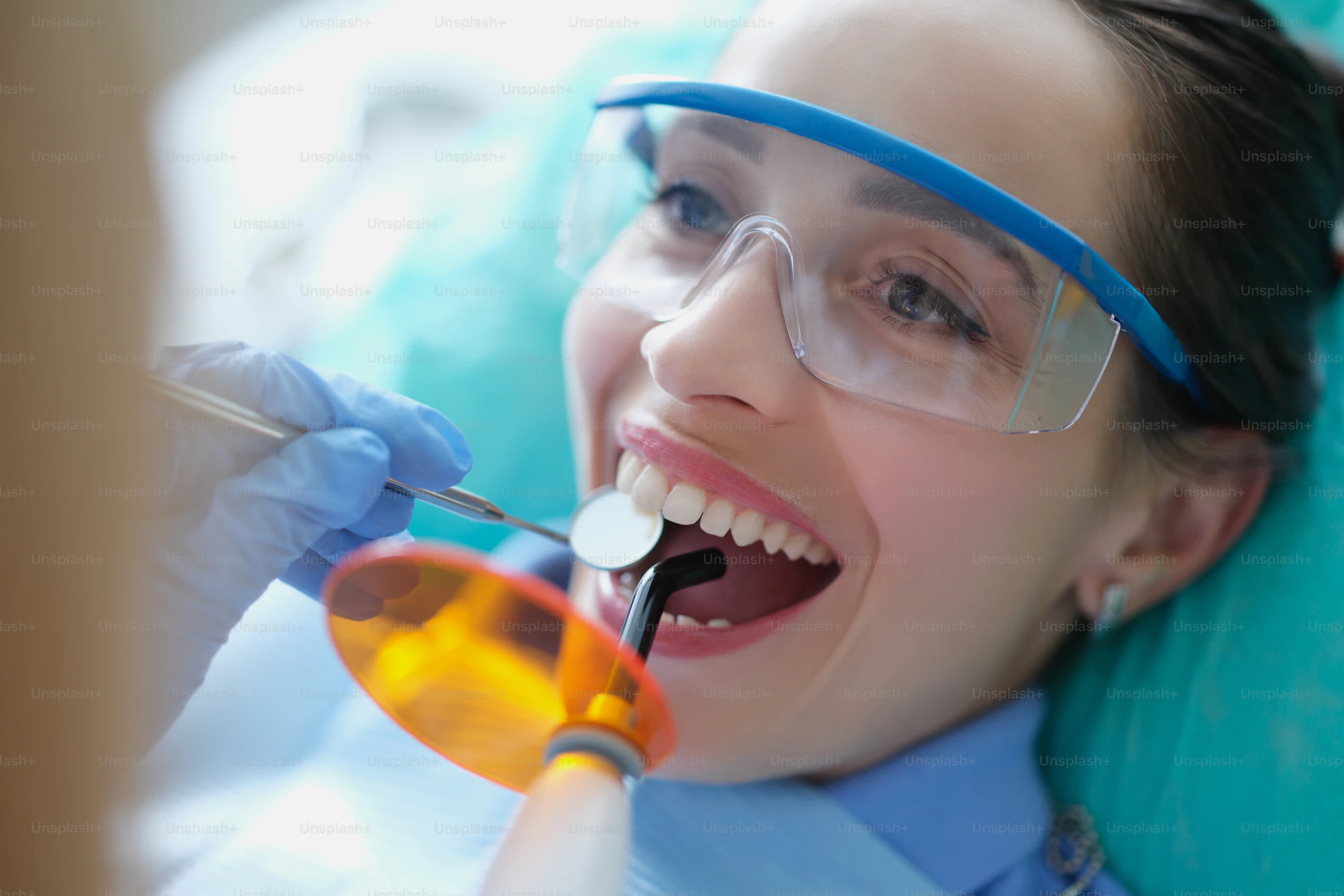 Dentist treating teeth with curing light and composite filling