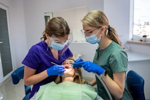 치과 의사와 그의 조수는 구강을 검사하고 고객을 치료합니다. 치아의 치료, 케어 컨셉