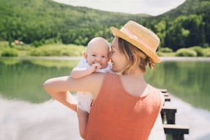 Mother and baby. Concept of natural maternity and motherhood. Beautiful woman and little baby happy together in green nature background. Loving mom with child outdoors.