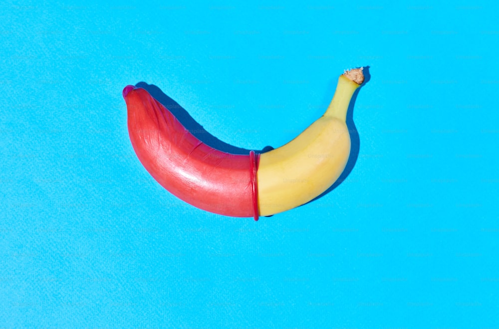 Prise de vue vibrante d’une banane unique avec un préservatif sur fond bleu chaud Concept de sexe sans risque et de protection, espace de copie