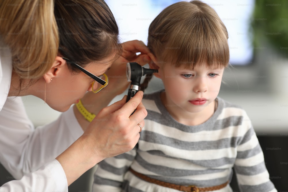 HNO-Arztin untersucht das Ohr eines kleinen Mädchens mit einem Otoskop in der Klinik. Diagnostik und Behandlung von Erkrankungen des Hals-Nasen-Ohres, der Nase im pädiatrischen Praxiskonzept.