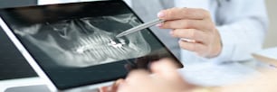 歯科医は錠剤で患者に顎のX線写真を見せます。歯科医師サービスのコンセプト