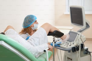 Gynecologist preparing for an examination procedure for a woman sitting on a gynecological chair