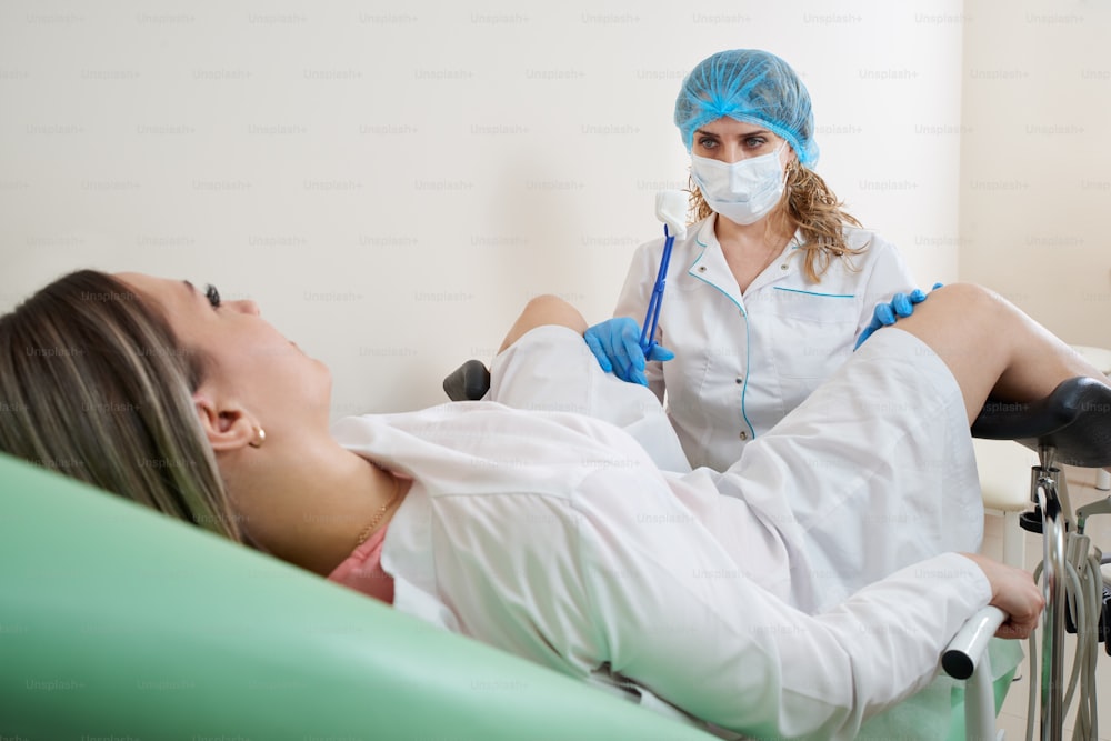 Ginecologo che si prepara per una procedura di esame per una donna seduta su una sedia ginecologica