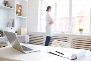 Background image of doctors office with woman standing at window copy space