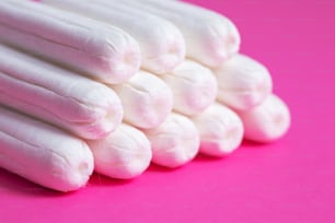 Medical female tampon close up on a pink background. Hygienic white tampon for women. Cotton swab. Menstruation, means of protection. Tampons on a red background.