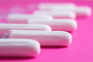 Medizinischer weiblicher Tampon Nahaufnahme auf rosa Hintergrund. Hygienischer weißer Tampon für Frauen. Wattestäbchen. Menstruation, Mittel zum Schutz. Tampons auf rotem Hintergrund.