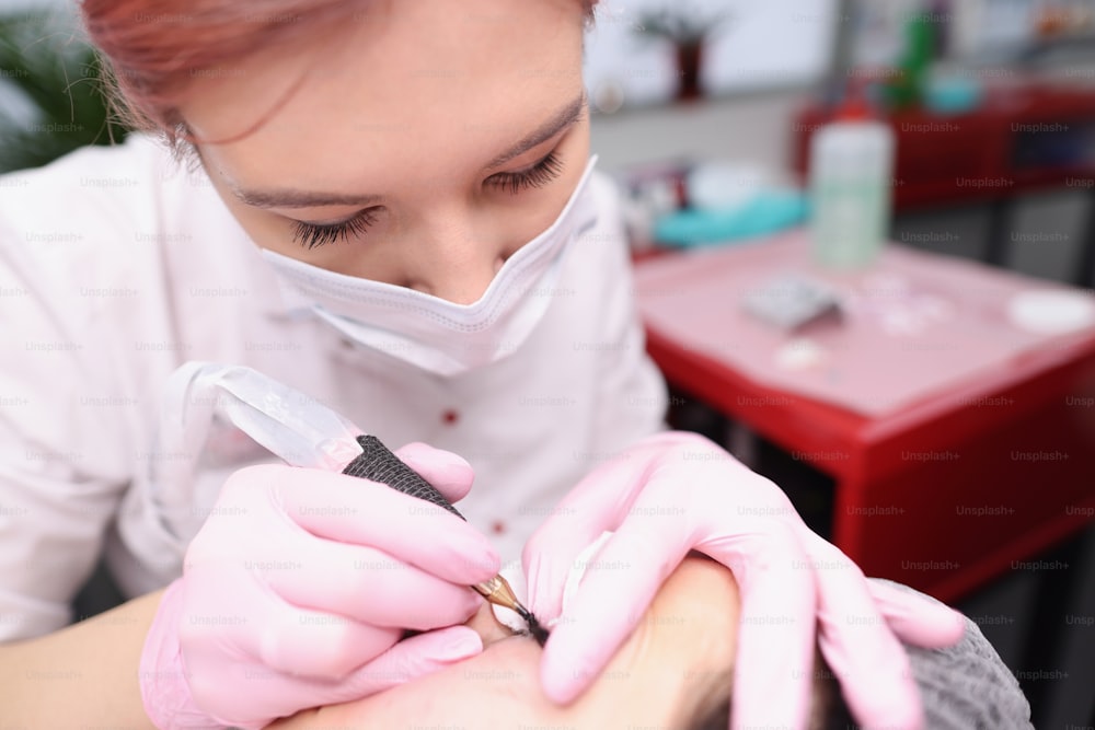 Il maestro cosmetologo fa un tatuaggio permanente delle palpebre nel salone di bellezza. Concetto di servizi di trucco permanente