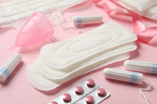 Accesorios del período de la menstruación sobre fondo rosa, primer plano