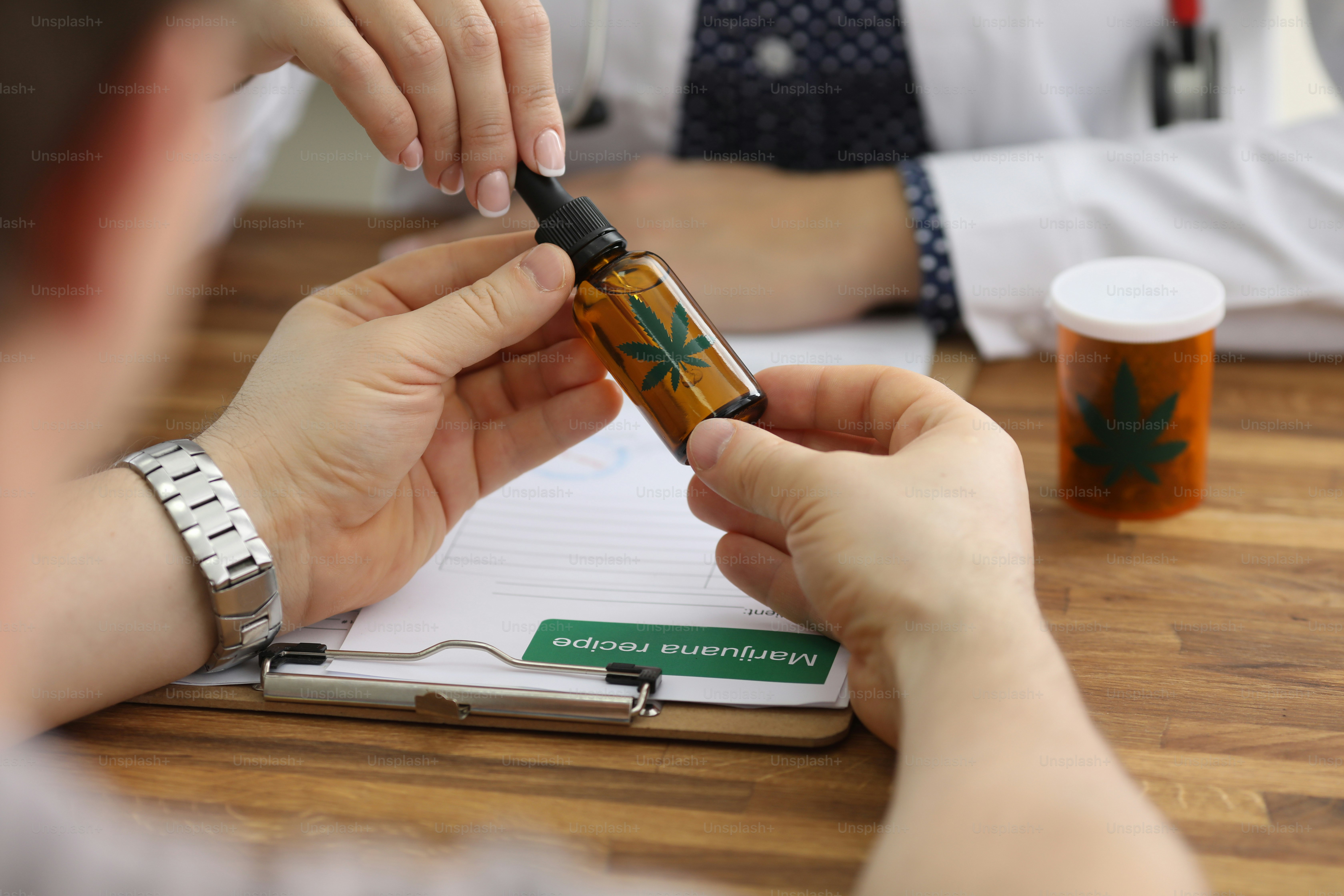 Close-up of patients hands holding bottle with cannabinoid oil. Female doctor preparing marijuana recipe. Folk treatment and alternative therapy concept