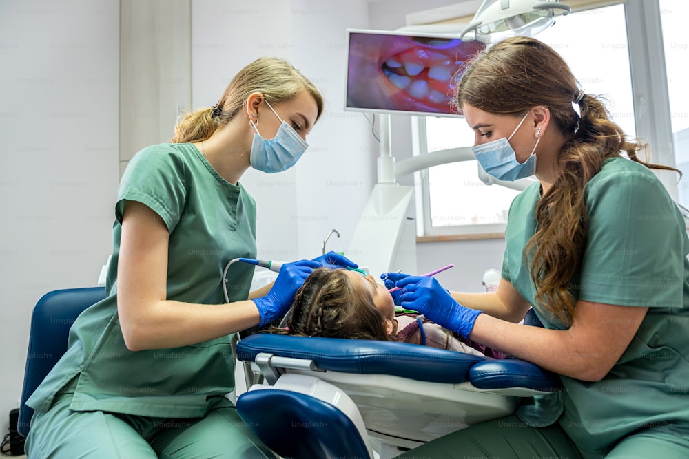 Der kleine Patient wird von Zahnärzten durch die auf dem Bildschirm angezeigte Kamera untersucht. Das Konzept, Kinderzähne mit einer Kamera zu untersuchen