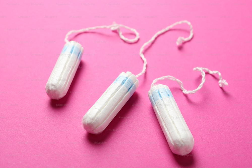Three tampons on pink background, close up